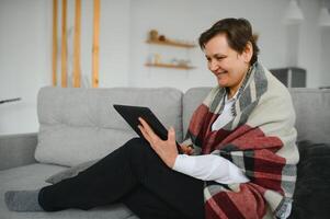 ziemlich Senior Frau mit Tablette Computer beim Zuhause foto