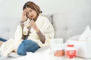 jung asiatisch Frau haben hoch Fieber während Überprüfung Körper Temperatur, weiblich Niesen und flüssig Nase mit saisonal Grippe, nehmen Medizin, Virus, Coronavirus, Erkrankung, Atmung, Allergiker foto