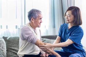 Senior asiatisch Mann habe medizinisch Bedienung Besuch von Pflegekraft Krankenschwester beim Zuhause während vorbereiten zum physisch Therapie und mit Salbe Reiben zum Muskel Schmerzen im Gesundheit Pflege und die Pension Wohlergehen Konzept foto