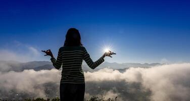 Panorama zurück Aussicht von Frau ist entspannend üben Meditation Yoga beim oben von neblig Berg mit steigend Sonne im das Sommer- zu erreichen Glück von innere Frieden Weisheit zum gesund Verstand und Seele foto