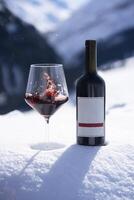 ein Flasche von rot Wein und ein Glas von Wein Sitzung auf ein schneebedeckt Boden foto