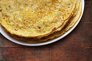 hausgemacht Pfannkuchen auf ein Weiß Teller auf ein hölzern Tabelle foto