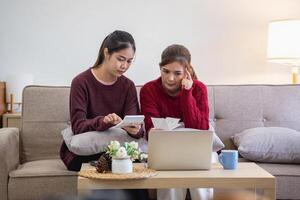 ein jung asiatisch Frau sitzt auf ein Sofa im ihr heim, Gefühl besorgt und frustriert Über ihr monatlich Kosten. verschiedene Nützlichkeit Rechnungen. foto