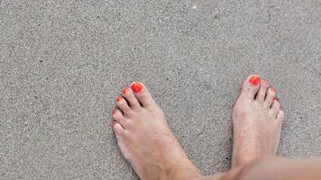 Damen Füße mit ein Pediküre im das Sand auf das Strand foto
