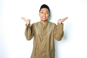 lächelnd asiatisch Muslim Mann tragen islamisch Kleid Dehnen Hand beiseite zu präsentieren leeren Raum mit öffnen Palme isoliert auf Weiß Hintergrund foto