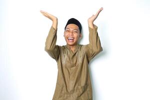 begeistert asiatisch Moslem Mann tragen islamisch Kleid erziehen Palme zu über präsentieren mit Lachen Ausdruck isoliert auf weiß Hintergrund foto
