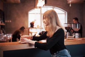 glücklich lächelnde junge Frau mit Telefon in einem Café. schönes Mädchen in trendigen Frühlingsfarben foto