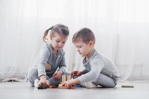 Kinder spielen mit einem Spielzeugdesigner auf dem Boden des Kinderzimmers. zwei Kinder spielen mit bunten Blöcken. Lernspiele im Kindergarten foto