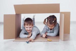 Babybruder und Kinderschwester spielen in Kartons im Kindergarten foto