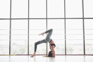 eine Sportfrau, die Yogastunden macht und ihre Beine in der Nähe des großen Fensters ausstreckt foto