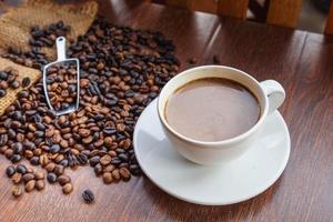 Tasse Kaffee und Kaffeebohnen in einem Sack auf braunem Hintergrund, Ansicht von oben foto