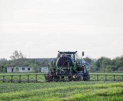 Traktor mit ein sprühen Gerät zum fein dispergiert Dünger. foto