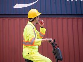 Fahrt Roller Mann männlich Auto Auto reden Radio Talkie Walkie Gelb Helm Sicherheit tragen Uniform Techniker Transport Arbeit Job Container importieren Export logistisch Ladung Auftragnehmer Versand Geschäft foto