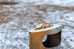 Zigaretten Stummel im ein Abfall Container im das Winter foto