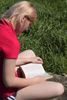 jung Frau liest Buch draußen im Natur foto