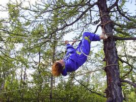 ein Tourist Mädchen klettert ein Seil zwischen das Bäume foto