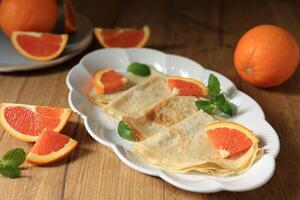 Crepes suzette mit Orange und Minze Blatt auf Oval Teller foto