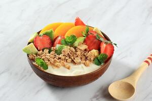 Schüssel von Granola griechisch Joghurt mit Erdbeere, Avocado, und Pfirsich Belag. foto