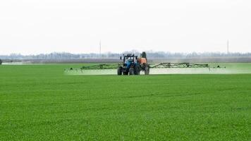 Traktor mit ein sprühen Gerät zum fein dispergiert Dünger. foto