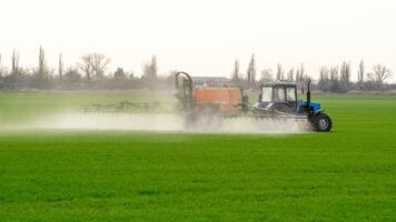 Traktor mit ein sprühen Gerät zum fein dispergiert Dünger. foto