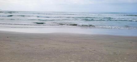 Bild von Strand mit Weiß Sand und Ruhe Meer auf sonnig Tag mit Badegäste und Surfer auf das Strand foto