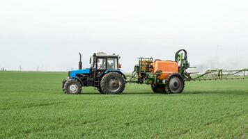 Traktor mit ein sprühen Gerät zum fein dispergiert Dünger. foto