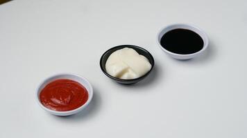 drei Saucen Ketchup Mayonnaise, Süss Soja Soße und Chili Soße im schwarz Schüssel isoliert auf Weiß Hintergrund foto