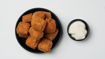 gebraten Tofu auf ein schwarz Teller mit Mayonnaise auf ein Weiß Hintergrund foto