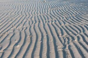 niedrig Winkel Aussicht von Linie Muster auf Sand erstellt durch Wellen im belitung Insel Strand, Indonesien. belitung ist einer von das die meisten Beliebt Tourist Ziele im Indonesien. foto