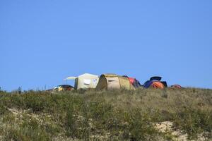 Tourist falten Zelte unter Küsten Vegetation. das Zelt ist modern. foto