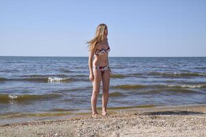 blond Mädchen im ein Bikini auf das Strand. schön jung Frau im ein bunt Bikini auf Meer Hintergrund foto