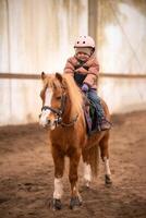 wenig Kind Reiten Lektion. Drei Jahre alt Mädchen Fahrten ein Pony und tut Übungen foto
