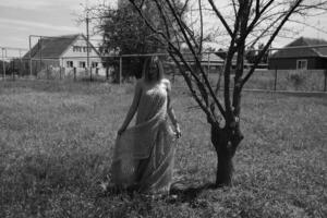 schwarz und Weiß Foto, Mädchen im das Garten auf ein Wiese im ein Kleid. foto