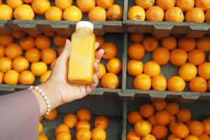 Frauen halten ein Flasche von Orange Saft gegen gegen Obst Hintergrund foto