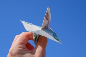 Konfessionen von Russisch Geld, gefaltet im das Flugzeug gegen das Blau Himmel im Hand foto