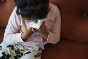 krank Kind mit Grippe Schlag Nase mit Serviette. foto