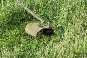 Anwendung Trimmer. Mähen Grün Gras mit ein Angeln Linie Trimmer foto