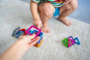 wenig Mädchen spielen bunt Magnet Plastik Blöcke Kit beim heim. das Kind spielen lehrreich Spiele. früh Kindheit Entwicklung. foto