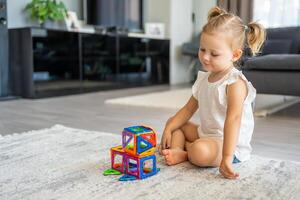 wenig Mädchen spielen bunt Magnet Plastik Blöcke Kit beim heim. das Kind spielen lehrreich Spiele. früh Kindheit Entwicklung. foto