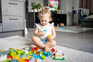 kaukasisch Kind ein wenig Mädchen ist spielen im das Konstrukteur beim heim. lehrreich Spielzeuge zum Kinder. foto