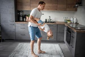 ein glücklich Vater und wenig Mädchen freudig Ausgaben Zeit im ein modern Küche. glücklich Familie. Vaters Tag. foto