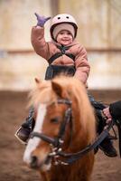wenig Kind Reiten Lektion. Drei Jahre alt Mädchen Fahrten ein Pony und tut Übungen. hoch Qualität Foto