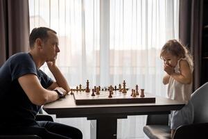 Vater Lehren seine wenig Tochter zu abspielen Schach beim das Tabelle im Zuhause Küche. das Konzept früh Kindheit Entwicklung und Bildung. Familie Freizeit, Kommunikation und Erholung. foto