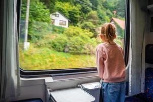 süß wenig Mädchen suchen aus Zug Fenster außen, während es ziehen um. Reisen durch Eisenbahn im Tschechisch Republik, Europa foto