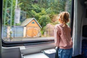 wenig Mädchen suchen aus Zug Fenster außen, während es ziehen um. Reisen durch Eisenbahn im Tschechisch Republik, Europa foto