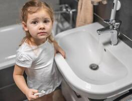 glücklich Kleinkind Mädchen Bürsten Zähne im das Bad foto