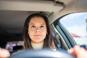 glücklich Frau Fahren ein Auto und lächelnd. süß jung Erfolg glücklich Brünette Frau ist Fahren ein Wagen. Porträt von glücklich weiblich Treiber Lenkung Wagen. foto