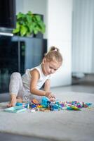 wenig Mädchen Theaterstücke mit klein Konstrukteur Spielzeug auf Fußboden im heim, lehrreich Spiel, Ausgaben Freizeit Aktivitäten Zeit Konzept foto