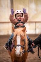 wenig Kind Reiten Lektion. Drei Jahre alt Mädchen Fahrten ein Pony und tut Übungen. hoch Qualität Foto
