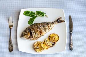 Gegrillter Dorada-Fisch mit Zitrone und Spinat foto